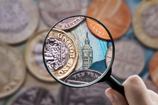 A magnifying glass held over a British one-pound coin and a ten-pound note featuring Big Ben, symbolizing a close analysis of the UK economy and the British Pound.